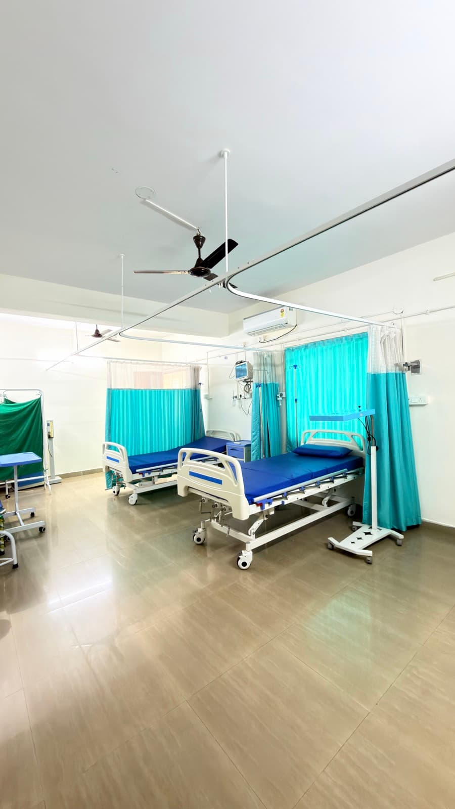 An air-conditioned ward. Adjustable beds, a monitor at each bedside, curtains between them.