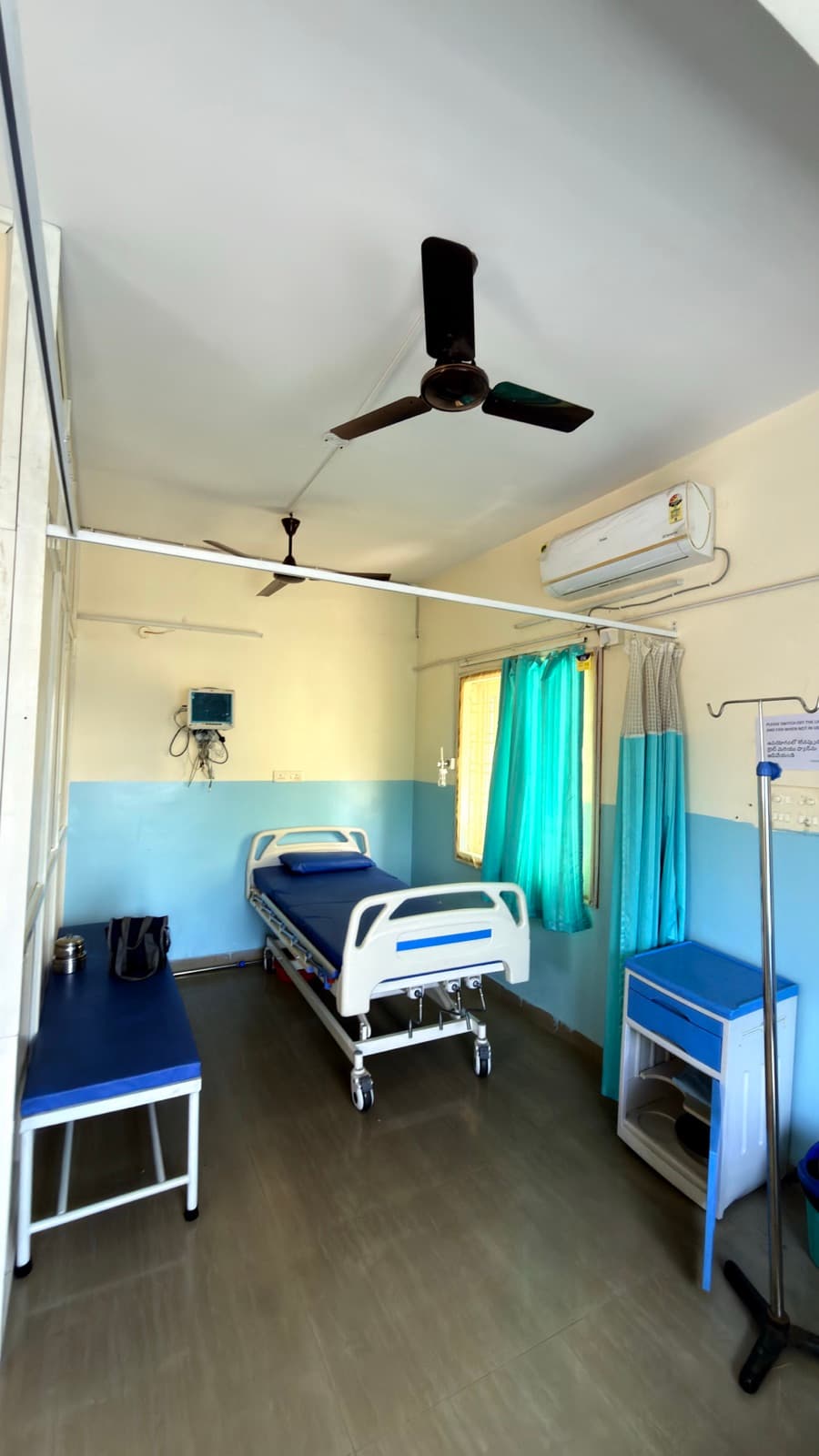 A private room, with a bedside monitor and a bench for the attendant who stays over.