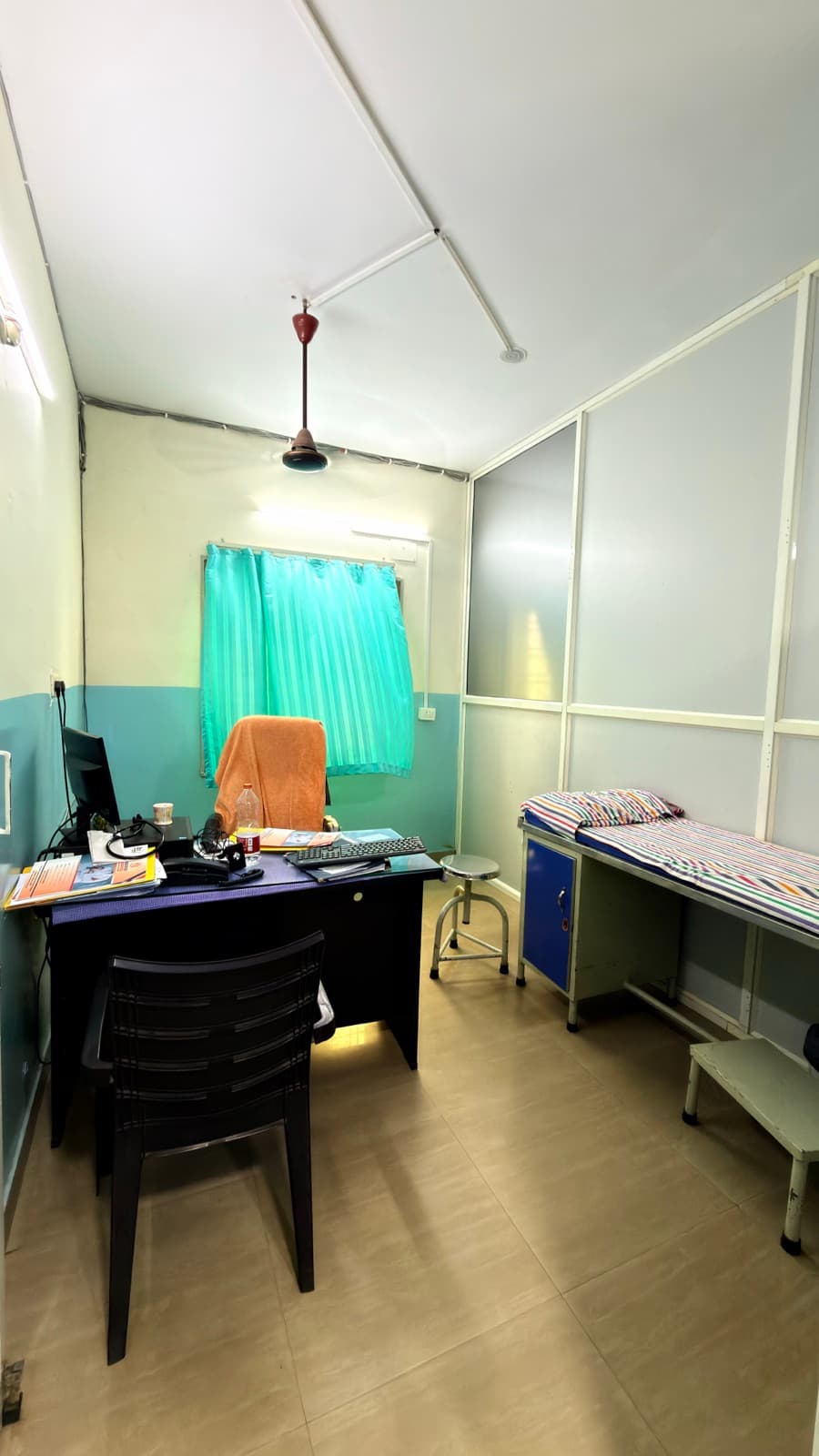 A consulting room — the doctor's desk on one side, the examination couch on the other.
