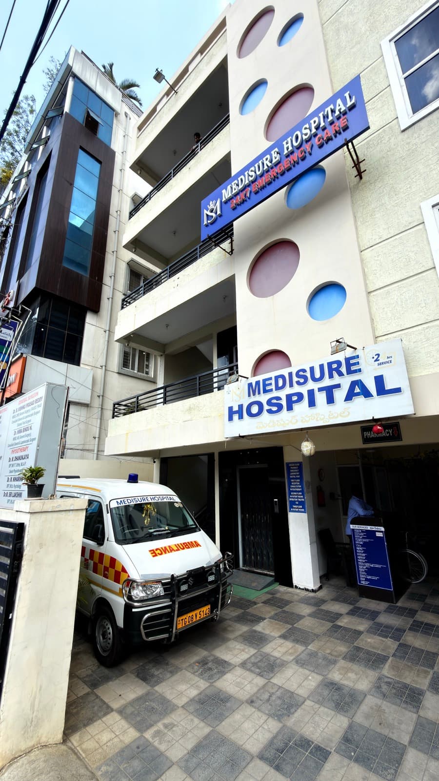 MediSure Hospital, Kukatpally — the main entrance, with the ambulance on standby.